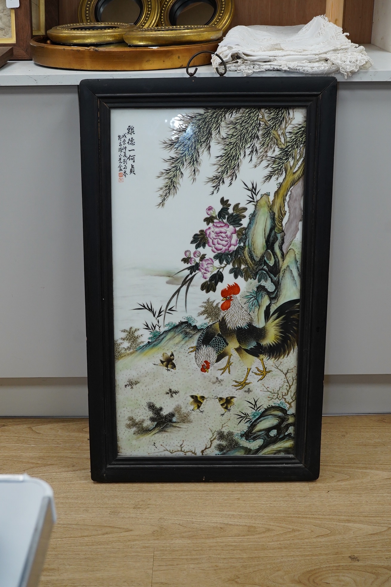 A Chinese famille rose porcelain plaque depicting cockerels and chicks before a landscape, signed with character marks and red seal mark, framed, 95cm high. Condition - good